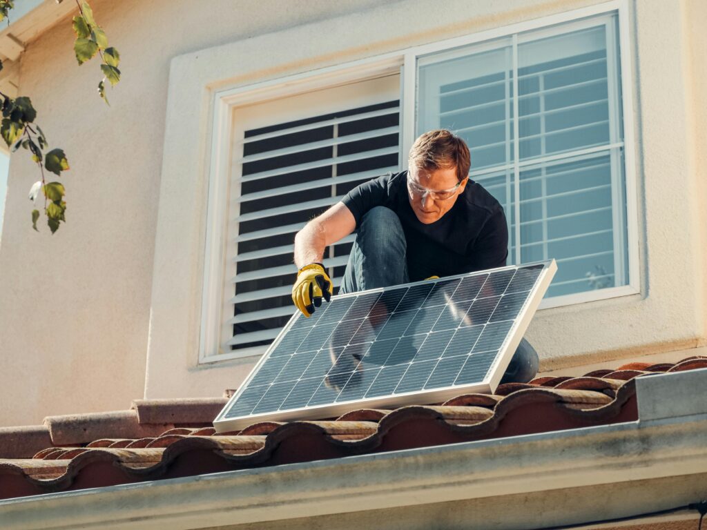Solar installer kneeling on a rooftop to service a panel